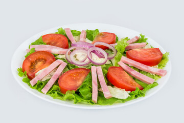 Salad in a white plate with ham, fresh tomatoes and herbs