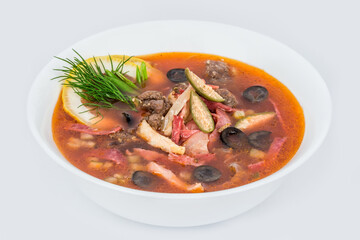 Solyanka soup in a white plate closeup shot on a white background