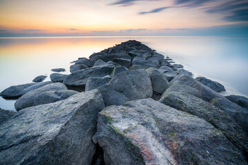Fototapeta na wymiar Waddenzee or wadd sea during sunset seen from jettywith stones ferry in dutch province of friesland