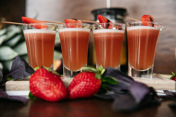 Strawberry shot cocktails set with basil on the stone board on the table in restaurant