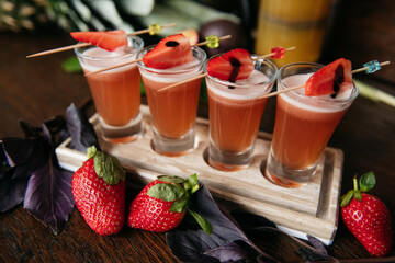 Strawberry shot cocktails set with basil on the stone board on the table in restaurant