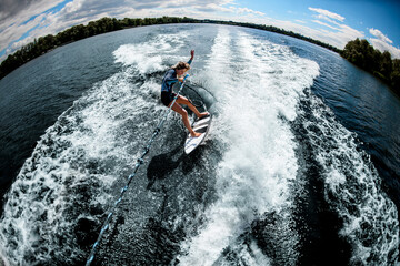 High angle view of woman riding on the wake surf holding rope of motorboat