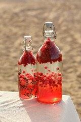 Cranberry juice in a bottle in the sunlight on the table.
