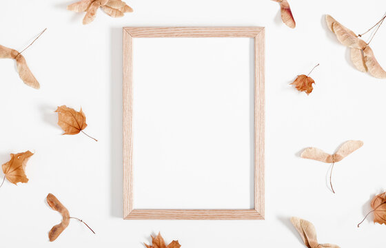 Autumn creative composition. Photo Frame, dry leaves, beige plaid on white background. Fall concept. Autumn background. Flat lay, top view, copy space
