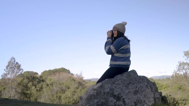 Woman taking photos on a rock of a mountain cliff