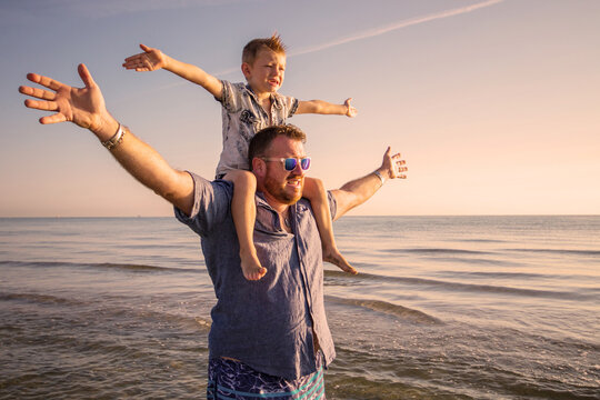 Happy father and son having quality family time on the beach on sunset on summer holidays. Lifestyle, vacation, happiness, joy concept