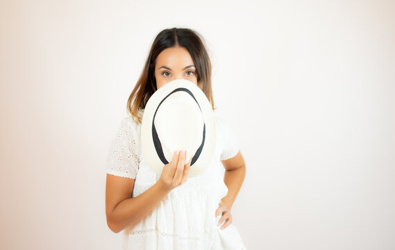 Woman covering half her face with a white hat