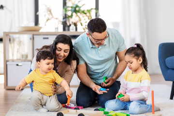 family and people concept - happy mother, father, little daughter and baby son playing with wooden toys at home
