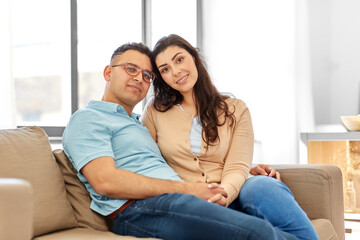 love, relationships and people concept - happy couple sitting on sofa at home