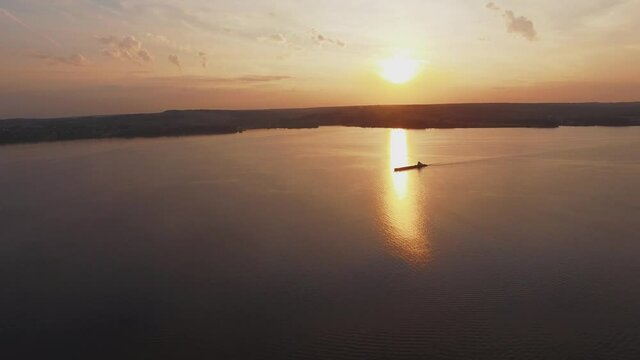 aero shot of the boat drifting at the river on sunset