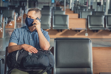 Man with a mask talking on mobile phone in airport lounge