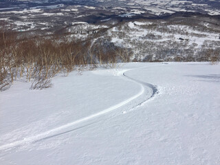 Fototapeta na wymiar Single snowboarding trail runs through fresh snow winter landscape Hokkaido Japan