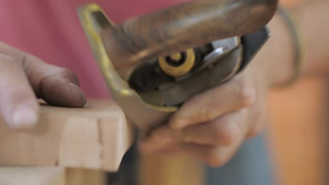 close-up.craftsman carpenter whittles workpiece of wooden board with jack-plane in a workshop. Woodworking and craftmanship concept.