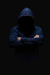 Fototapeta na wymiar Man in dark blue hoodie, face hidden in shadow, unrecognizable, crossed arms, alone in dark 