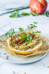 Sandwich with vegetable paste on a plate and a red tomato in the background