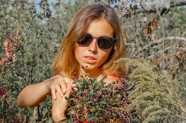 Pretty woman in sunglasses with branches with black berries