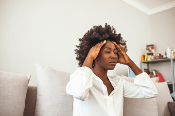 Young black woman suffering strong headache. Shot of a young woman experiencing a difficult moment. Shot of a young businesswoman looking stressed. Shot of a young woman experiencing a bad headache