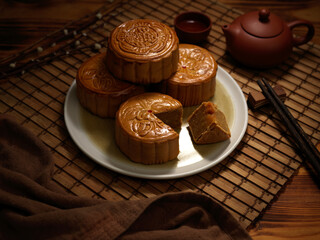Close up view of traditional moon cakes on plate and tea set on bamboo placemat