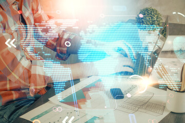 Double exposure of world map hologram with man working on computer on background. Concept of worldwideweb.