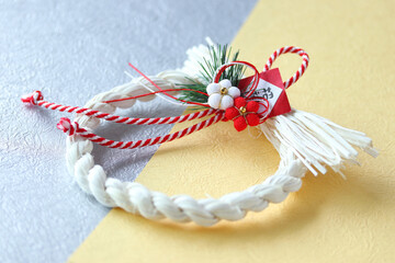 和紙の上の白いしめ縄リースと正月飾り（クリーム色と銀色）