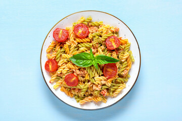 Fusilli - classic italian pasta from durum wheat with chicken meat, tomatoes cherry, basil in tomato sauce in white bowl on blue wooden table Mediterranean cuisine Top view Flat lay