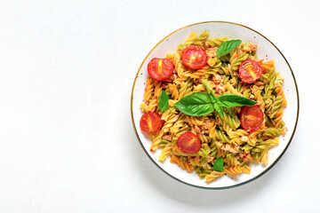 Fusilli - classic italian pasta from durum wheat with chicken meat, tomatoes cherry, basil in tomato sauce in white bowl on wooden table Mediterranean cuisine Top view Flat lay