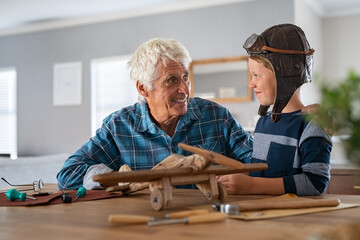 Happy grandfather build a wooden airplane with his grandson