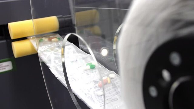 Strip of packaged pills moving from wheel through production line