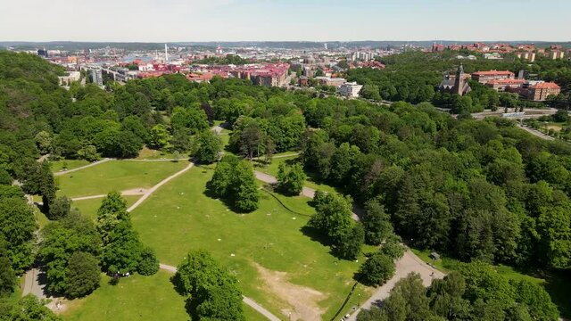 Natural Forest Park With Urban Landscape At The Background During Daytime In Slottsskogen, G&ouml;teborg, Sweden. - Aerial Drone Shot