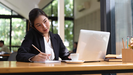 Businesswoman talking on the phone while working in office room