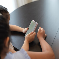 Two cute girls watching video on smartphone in living room