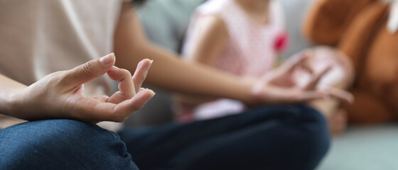 Female rest on sofa meditating with mudra hands on her lap, practicing yoga in living room