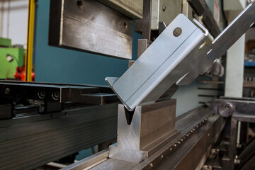 Bending sheet metal on a hydraulic machine at the factory. Bend tools, press brake punch and die. Close-up.