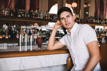 Young man resting in restaurant with drink near bar counter
