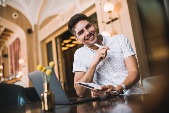 Cheerful young man with clipboard in modern workplace