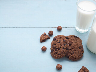 Homemade double chocolate chip cookies on blue wooden background with glass of milk. Copy space..