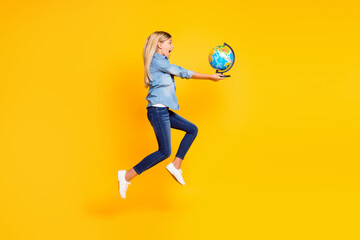Full length body size photo of amazed happy jumping high blonde girl holding globe screaming loudly isolated on bright yellow color background