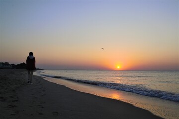 Girl walking on the beach at sunrise