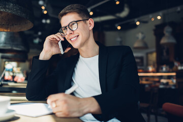 Positive male communicating on smartphone while resting in cozy cafe
