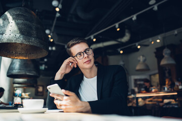 Young cafe manager with smartphone and cup of coffee