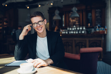 Positive restaurant administrator with cup of coffee and smartphone