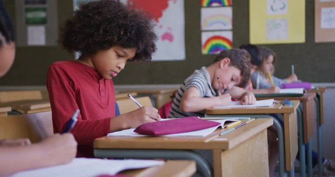 Group of kids writing while sitting on their desk in class at school