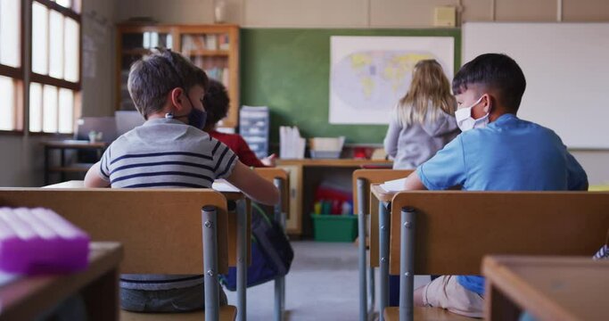 Two boys wearing face masks greeting each other by touching elbows at school