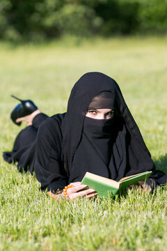 Islamic faith girl reads a quran book. Islamic faith girl reads a quran book lying on grass.