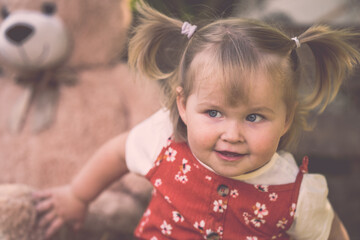 Süßes Kleinkind Mädchen mit rotem Kleid und Zöpfen großer Teddybär Sonnenschirm lächelt outdoor hölzener Hintergrund vintage Var. 10