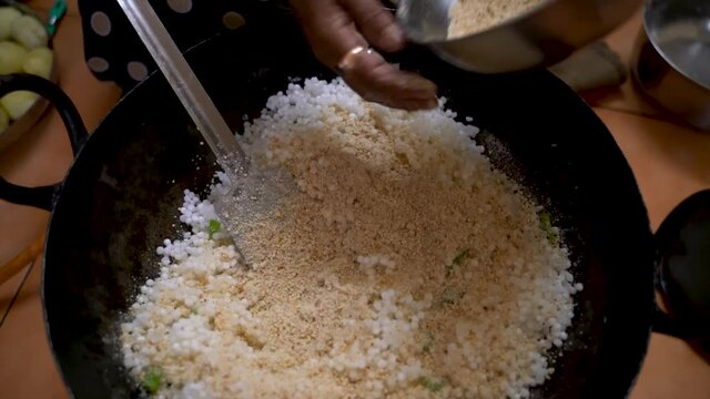 Adding The Peanut Powder On The Sago Polenta With Chili In A Metal Pan (Kadhai). - Close Up-topdown Shot 