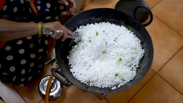 Sago Polenta In A Pan With Chili Over A Stove Being Cook By A Lady Seated On The Floor At The Kitchen. - High Angle Shot 