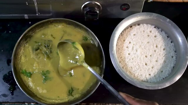 Cooked Maharashtrian Kadhi Stirring By A Scoop Ladle Next To Steamed Rice In A Pot. - Close up-topdown