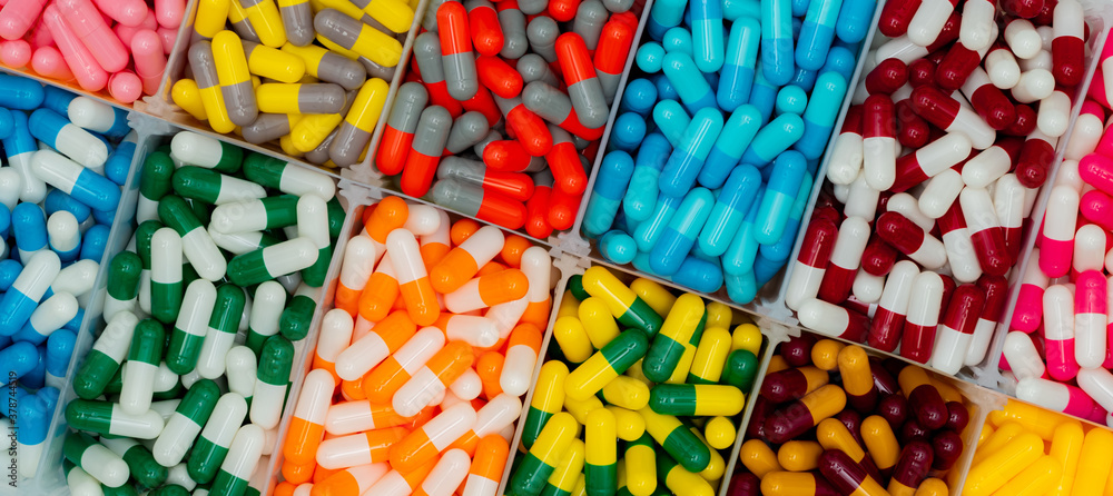 Wall mural top view of colorful capsule pills in plastic box. antibiotic drugs, painkiller medicine, vitamins, 