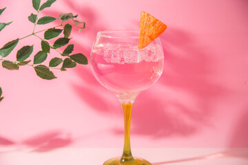 gin and tonic glass on pink background